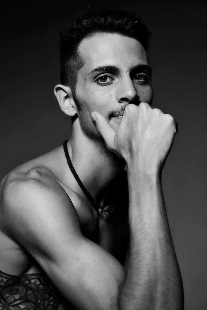 man wearing necklace in grayscale photo